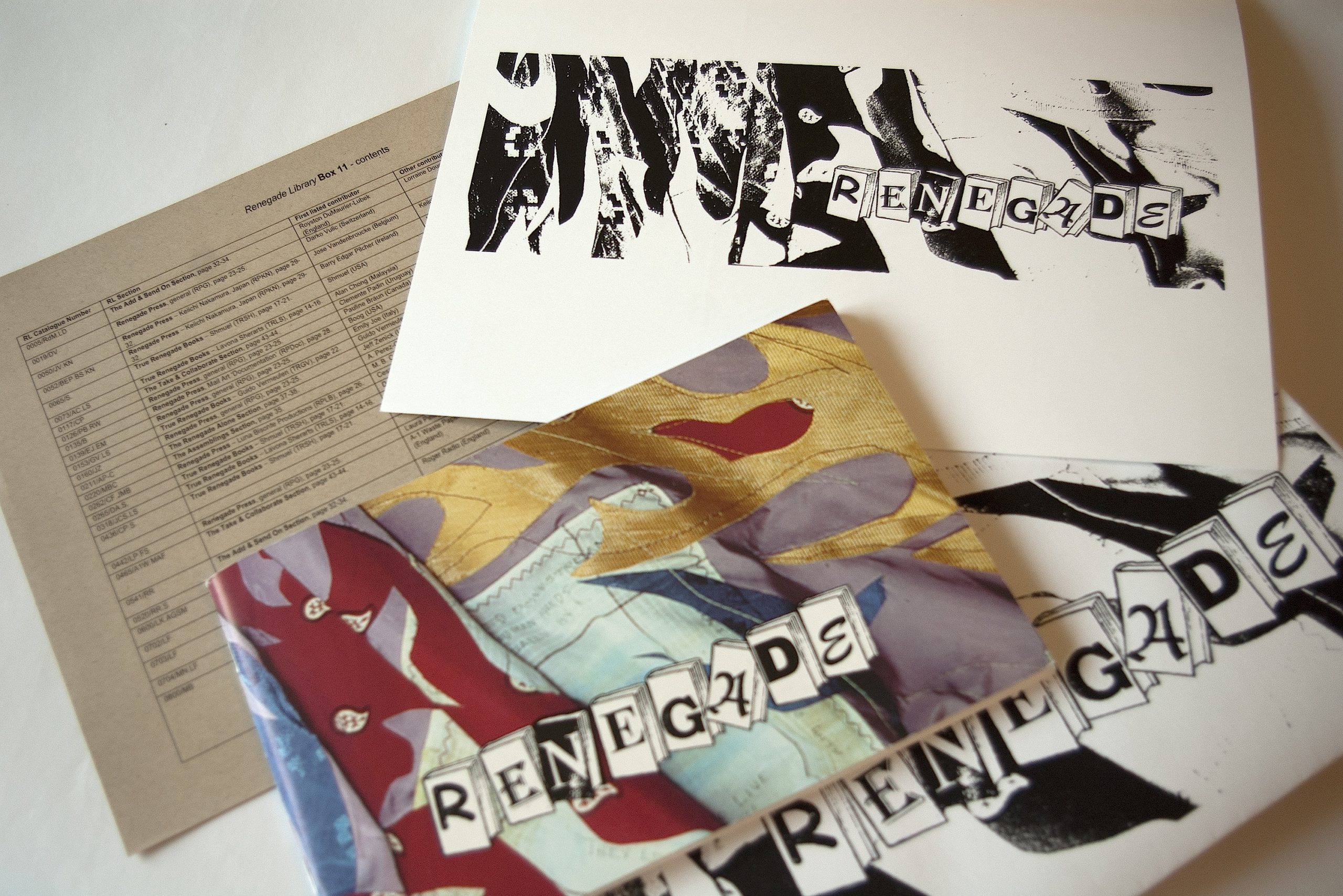 Materials from the interior of Renegade Library Box #13 including an exhibition catalogue with brightly coloured fabric pieces cut in flame or fire shapes. The other items have the same graphic in black and white.