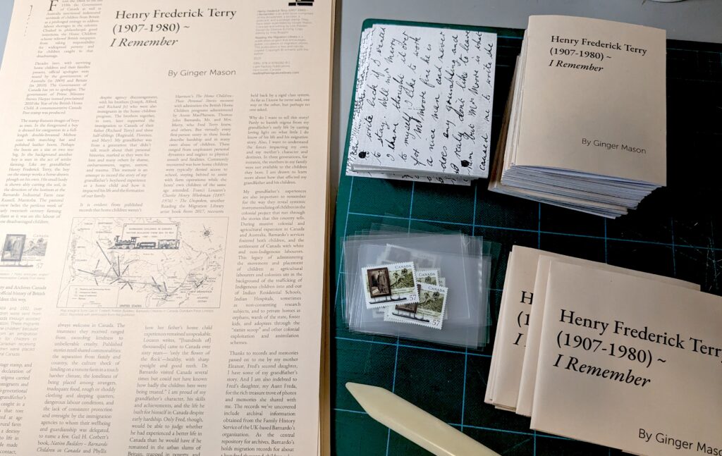 Pieces of the artist book are in piles waiting to be assembled (broadsheet, postcard, postage stamp, and booklet). A bone folder tool is also seen on the workspace.