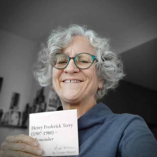Ginger Mason, a white woman with glasses and curly grey hair, is holding a copy of her RML book "Henry Frederick Terry"