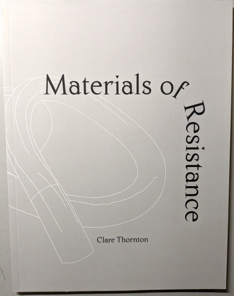 A grey artist's catalogue called "Materials of Resistance" from the exhibition by Clare Thornton.