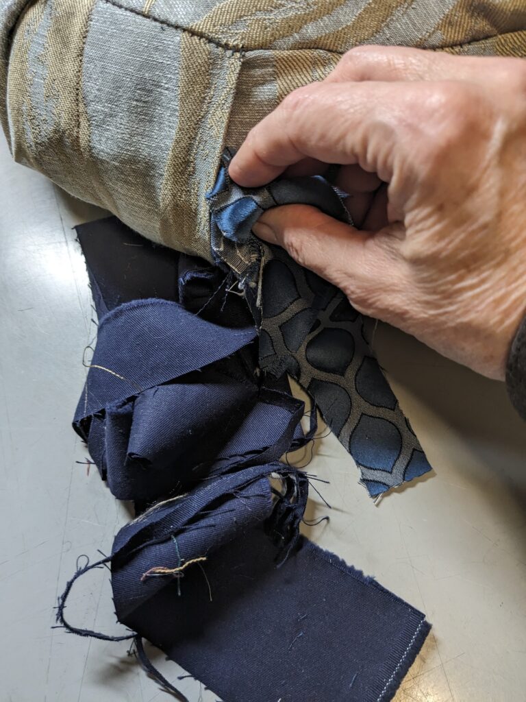 A hand is stuffing a meditation cushion with scraps of fabric.