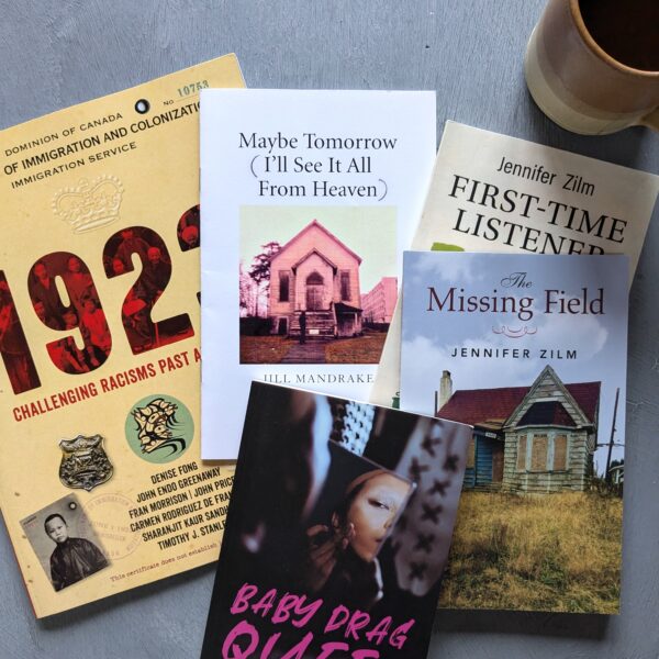 Five books are spread on a table with a pottery mug in the top right corner.