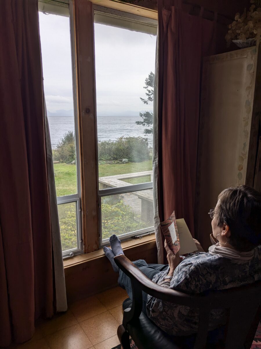 Lois Klassen reads by the window with a view onto the Salish Sea.