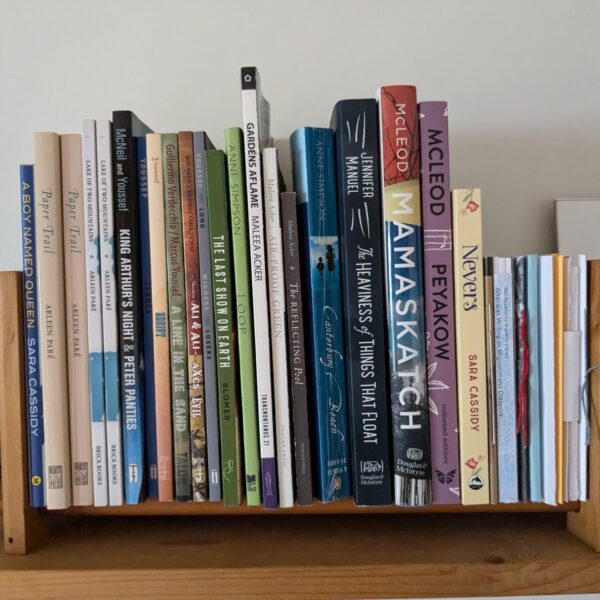 A small wooden shelf holds about 20 poetry chapbooks and memoirs.