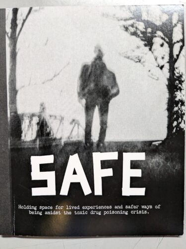 SAFE zine cover fills the frame. It features a black and white photo produced by a pin hole camera. The photo shows a fuzzy silhouette of a single human figure framed by trees.