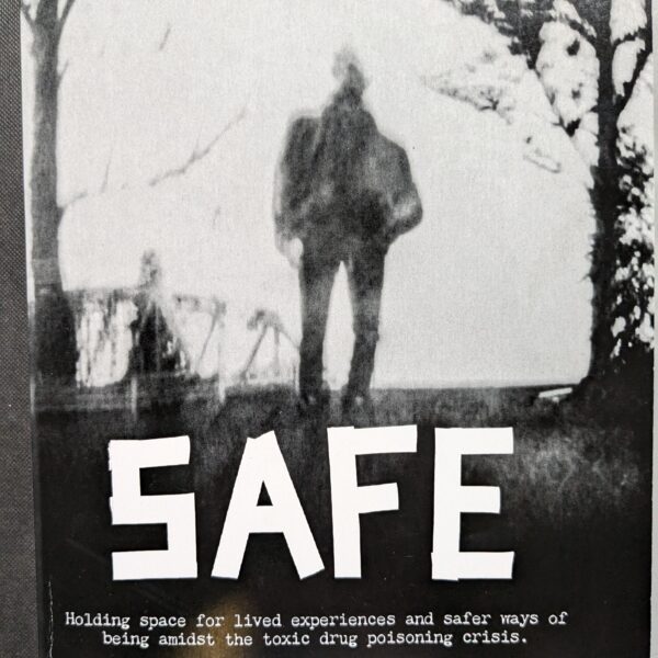 SAFE zine cover fills the frame. It features a black and white photo produced by a pin hole camera. The photo shows a fuzzy silhouette of a single human figure framed by trees.